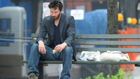 Keanu sitting on a bench, sad and eating.